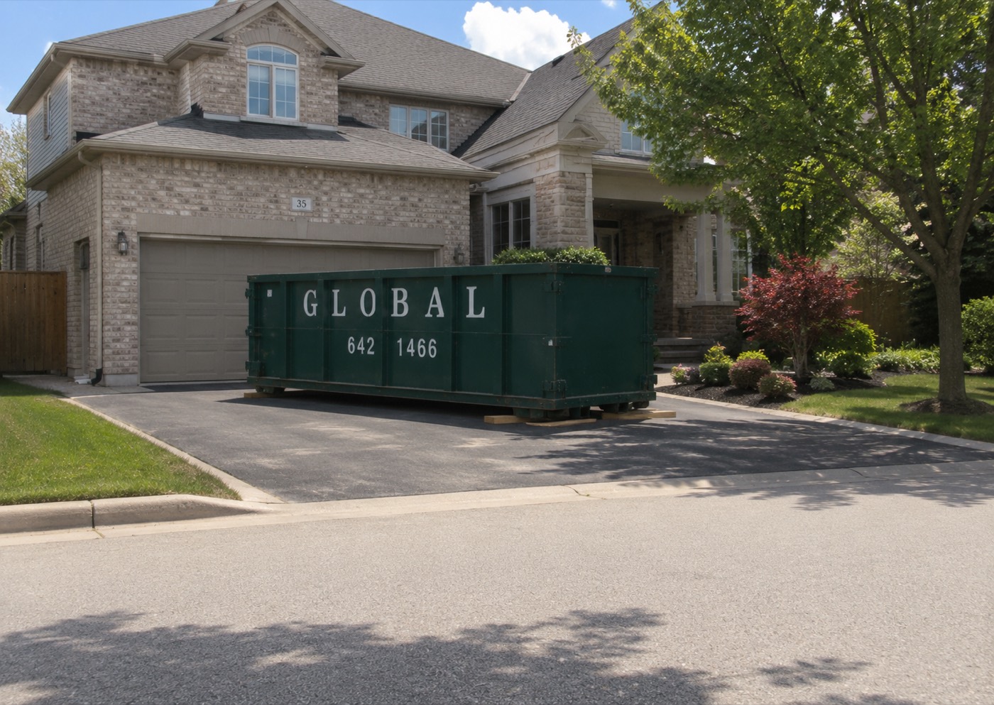 Global Waste Removal truck delivering a dumpster to a residential driveway